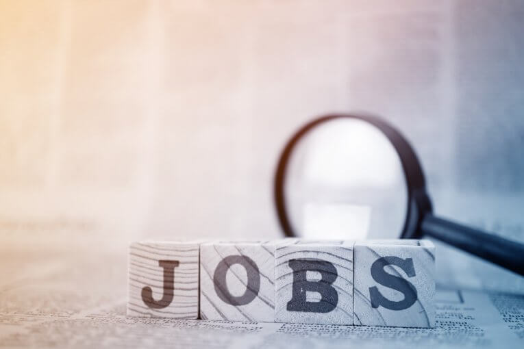 Holzklötze mit Aufschrift "Jobs" vor Lupe