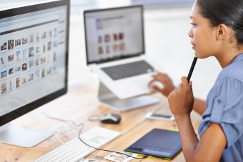 Junge Frau sitzt vor Computerbildschirm und Laptop