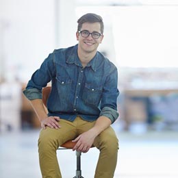 junger Mann mit Brille sitzt auf einem Stuhl