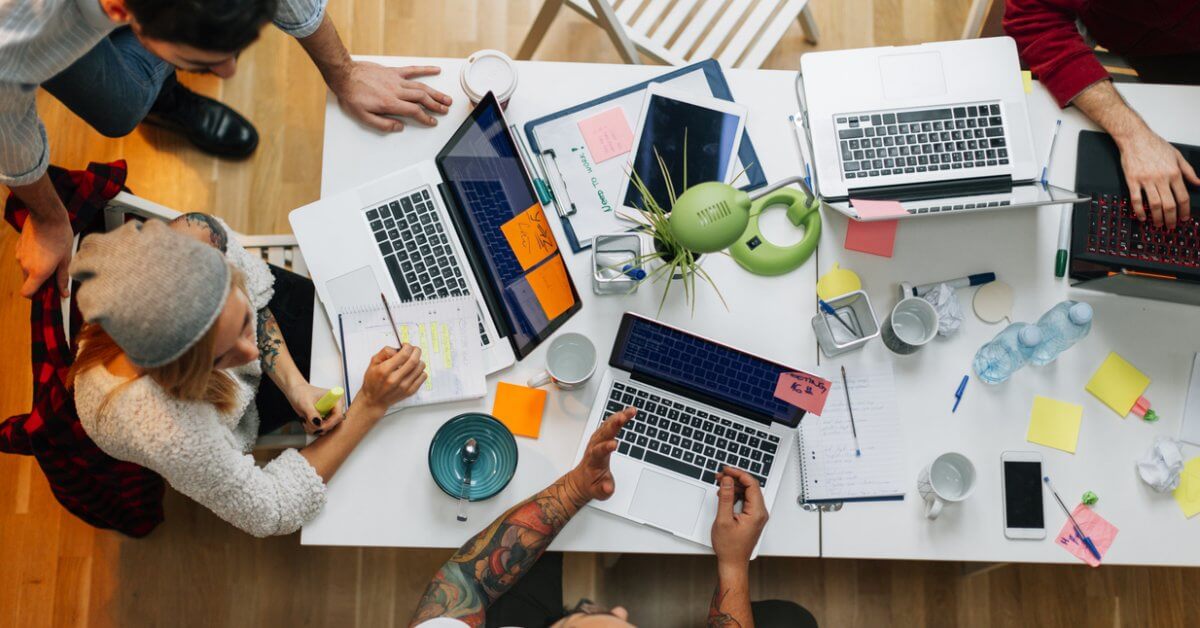 Blick von oben auf Schreibtisch, um den junge Menschen mit Laptop sitzen