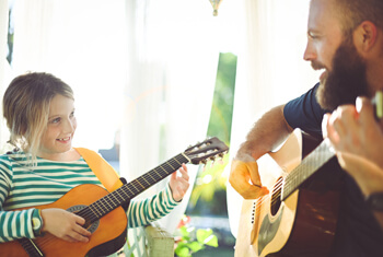 Musiktherapeut spielt Gitarre mit Kind